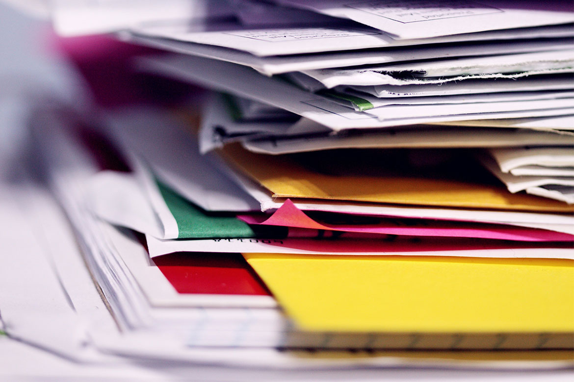 A stack of folders full of paper-based invoices, purchase orders, and shipping documents.