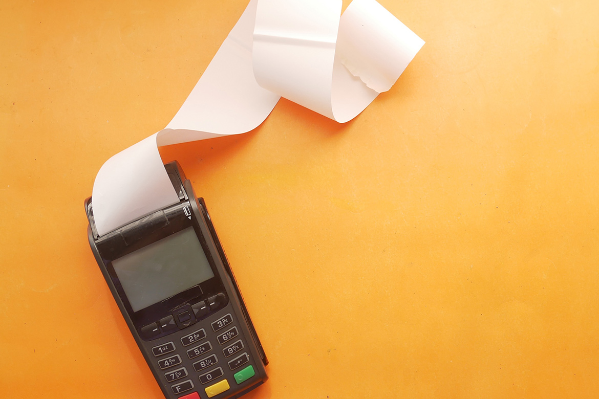 Photo of a credit card receipt terminal and receipt paper.